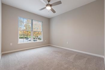 An empty room with a large window and a ceiling fan